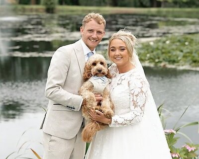 bride and groom holding their dog and smiling