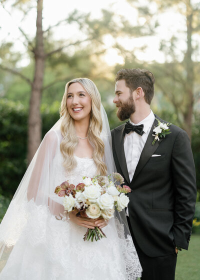 Bride in wedding dress standing with groom in white jacket