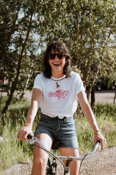 Playful summer branding photo of a woman on a bike, shot in a Silverthorne neighborhood.