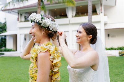 A newlywed putting a flower crown on a wedding guest 