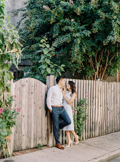 Candid moment during an editorial engagement session in a lush Seattle backyard garden with natural wood fencing.