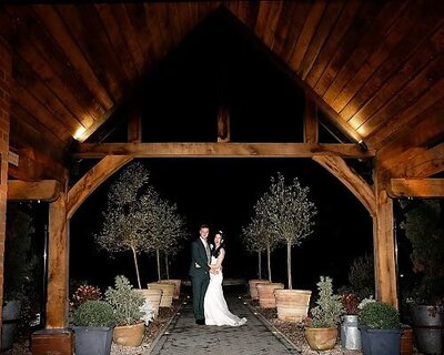 bride and groom with their arms around each other standing under archway laughing