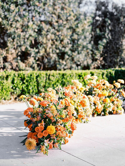 Orange floral arrangements lined up on the ground