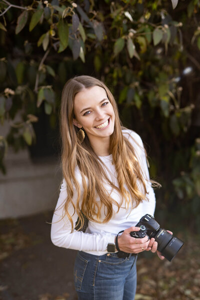 Woman holding a camera smiling