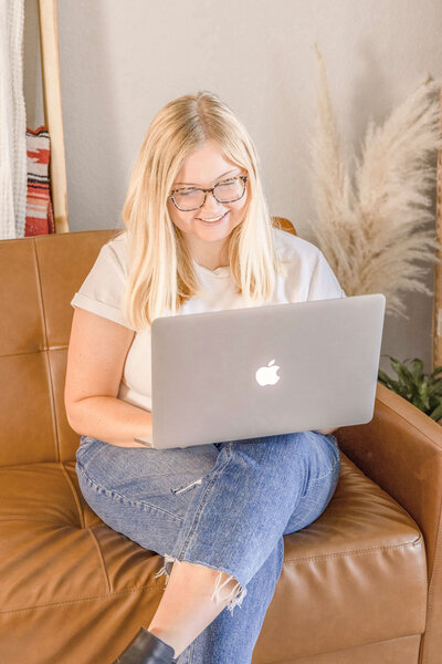Woman smiling and sitting on couch with laptop
