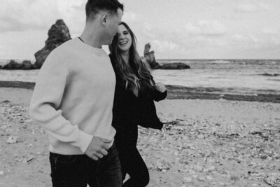 black n white image of B & T running on the beach