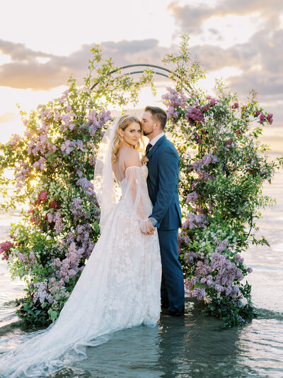 bride and groom with flower arch in lake