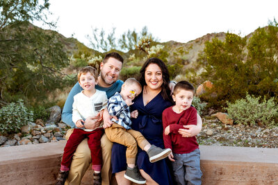 Family snuggled up and smiling while sitting for Cactus & Pine Photography