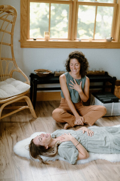 Woman laying on the floor doing breathing work with an instructor at Alyn Wellness Studio