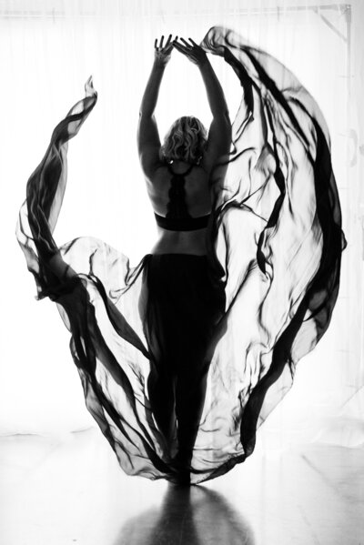 Black and white boudoir photo of a woman throwing chiffon fabric