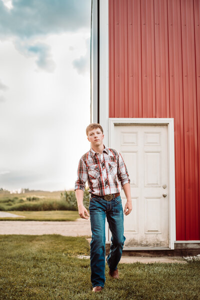A young man posed next to Iowa barn. 