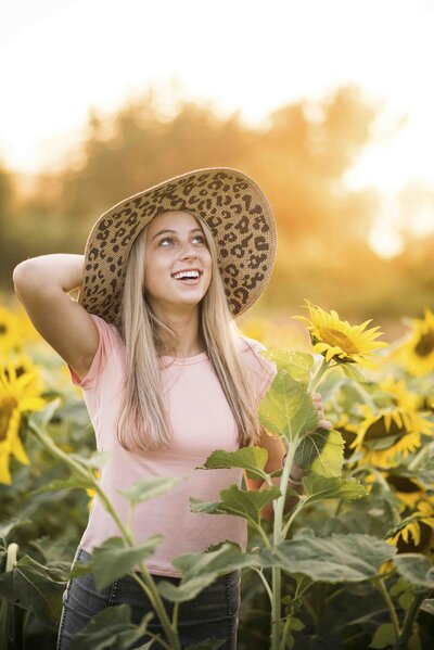 a girl in a white dress smiling while standing next to flowers in a window box