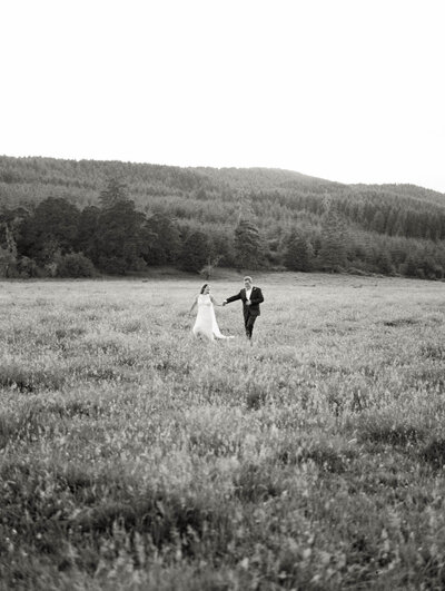 Bride and Groom running in open field