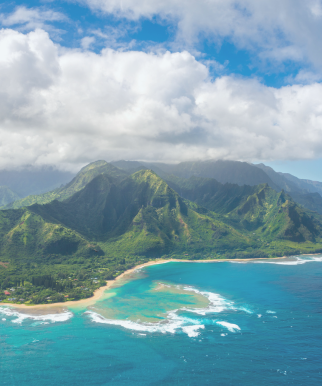 Aerial view of Hawaii with turquoise waters, lush green mountains, and a partly cloudy sky – tropical island paradise.