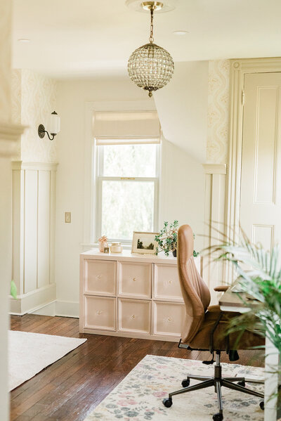 A view of a home office makeover featuring board and batten trim, a desk chair and a pink cube shelf turned into a new furniture piece.
