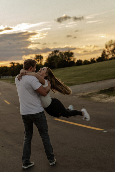 Outdoor Engagement Photo of boyfriend spinning girlfriend in a playful way in St Paul, MN 