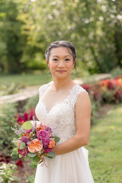 A bride at Hope Flower Farm wears a white wedding dress and holds a bouquet of beautiful flowers while smiling