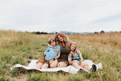 Libby and her kids sitting outside in a field.