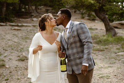 a bride and groom kiss after popping a bottle of champagne after their idaho springs elopement