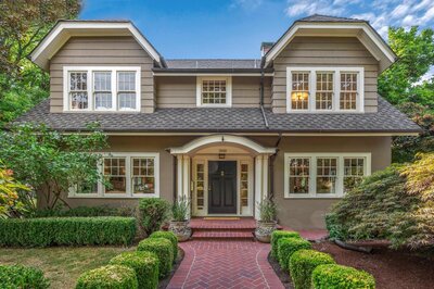 The front of a two story house with a brick walkway leading up to it.