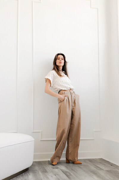 woman in a chic french style room standing against a wall looking at the caemra