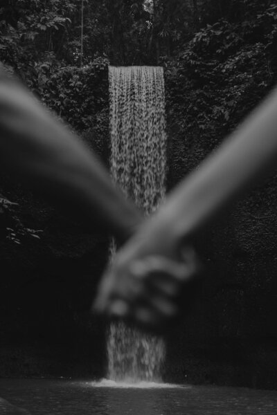 bride and groom pose on bridge by waterfall in Bali