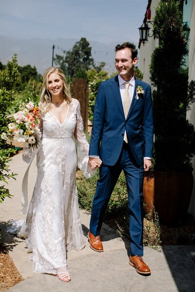 Smiling Bride and Groom walk through the vineyards before their Ojai Wedding.