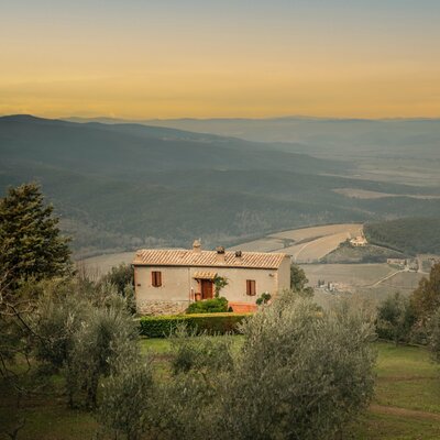 An old house sitting in the middle of a picturesque rural mountain scene in Italy