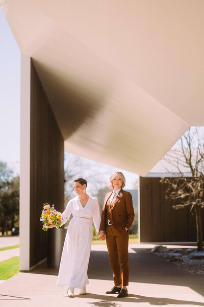 Two brides pose for an outdoor portrait before their wedding