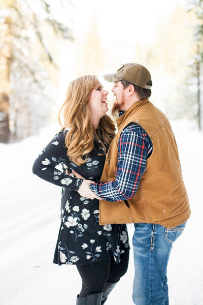 A man and woman during an engagement photography shoot, smiling and embracing each other.