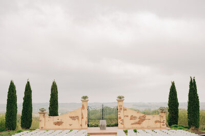 The Gates at Bella Terre - an Omaha wedding venue serve as the backdrop for a ceremony. Photo by Anna Brace, a wedding photographer in Omaha NE.