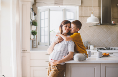 boy is hugging his pregnant mother from behind