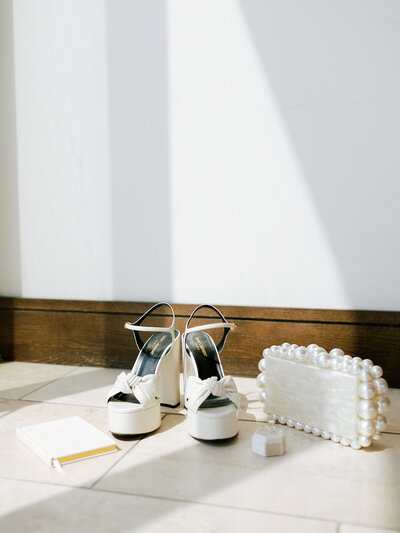 White platform heels on beige floor next to pearl clutch