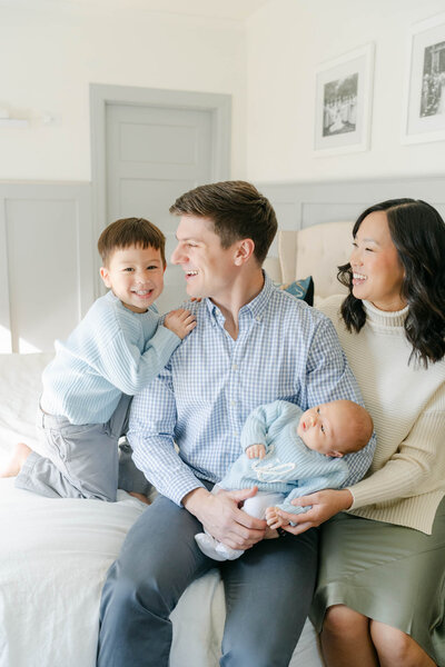 baby boy in cream wool sweater and brown romper sits on a log during a photo session with AnneMarie Hamant