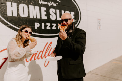 bride and groom eating pizza during wedding photos