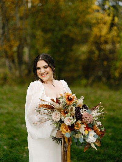 Bride holding fall wildflower bouquet with rudbeckia, roses, chocolate queen annes lace and pampas grass at  Pole Creek Ranch in Sisters Oregon