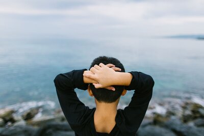 A little boy hold his hands behind his head. Looking out the blue waters of Waikiki Beach..