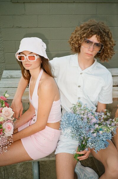 man and woman sitting on a bench holding flower bouquets