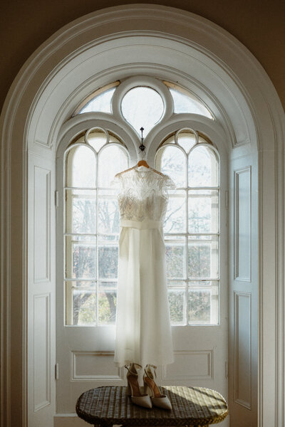wedding dress hanging in a beautiful arched window