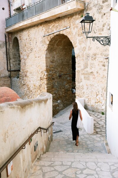Women walking away by old stone stairs and an arch