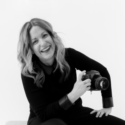 woman smiling while standing in a field holding a camera
