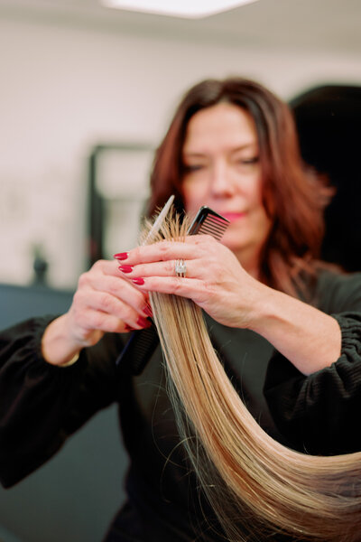 A hair stylist holding up hair as they cut it in a salon
