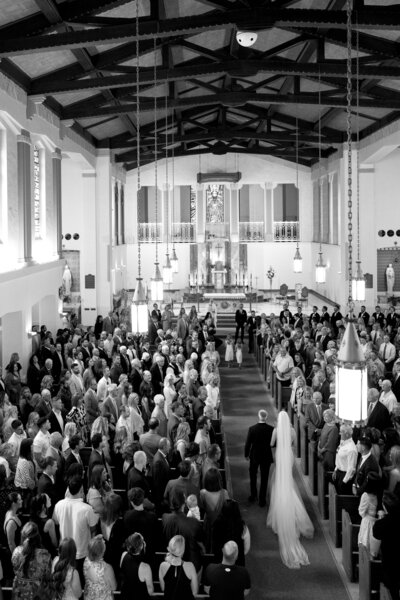 Black and white photo of bride being walked down the aisle by father in Bozeman montana church