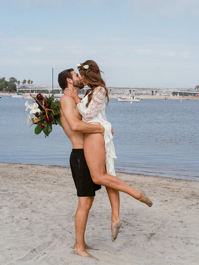 A couple celebrating their unique paddleboard elopement on the serene waters of San Diego. Captured by a talented California adventure wedding photographer, this image showcases the couple's love and the picturesque beauty of their unconventional elopement.