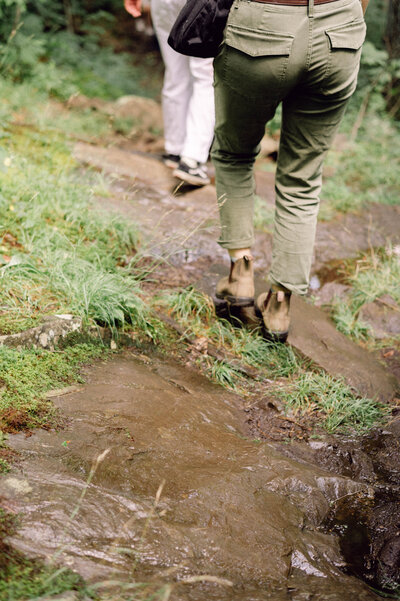 Close-up of the couple’s hiking boots resting on a mountaintop trail during their adventurous Virginia elopement, captured in a candid, editorial style.
