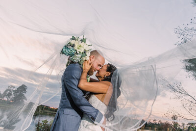 Brad Gillespie pulls his wife in for a kiss underneath her wedding veil