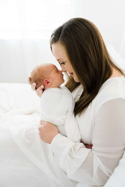 Mom holding baby snuggling noses