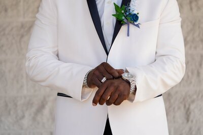 Close-up of groom adjusting watch and wedding ring before ceremony.