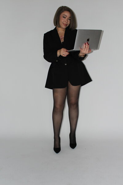 Bri Davis, Founder of Allure Atelier, smiling and holding an open laptop