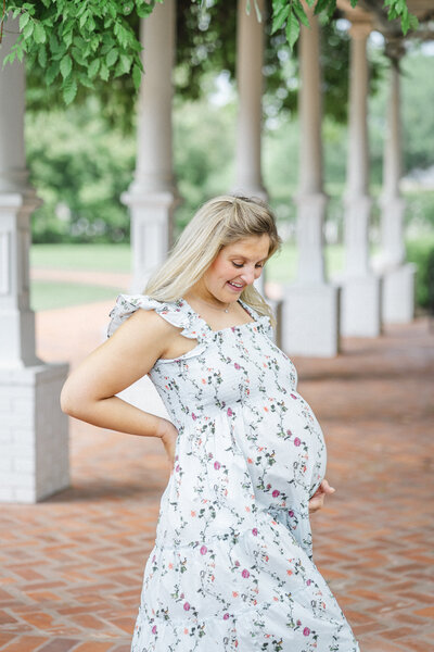 Photographer Round Rock TX | A pregnant mother stands by a row of columns in the courtyard of Woodbine Mansion in Round Rock, TX.